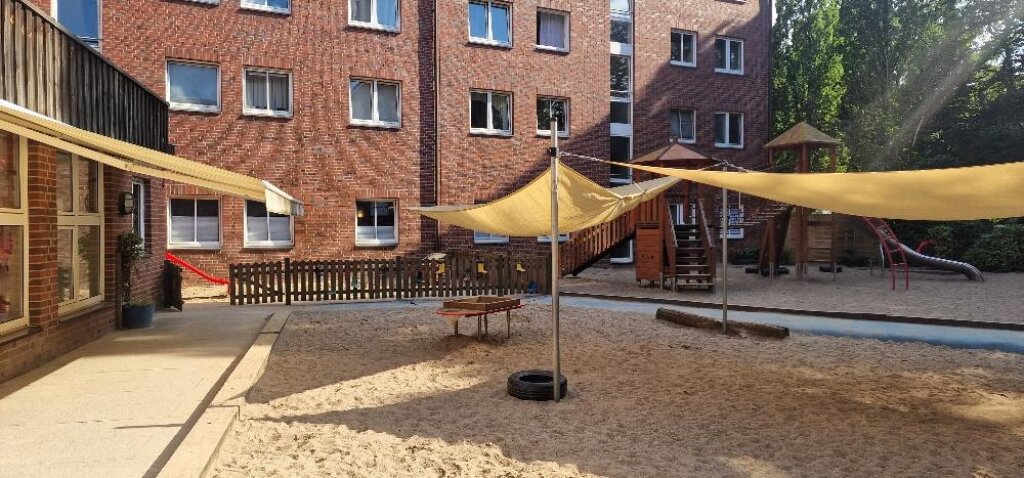 Außengelände mit Sandkasten und Sonnensegel der AWO Kita Auenstraße.