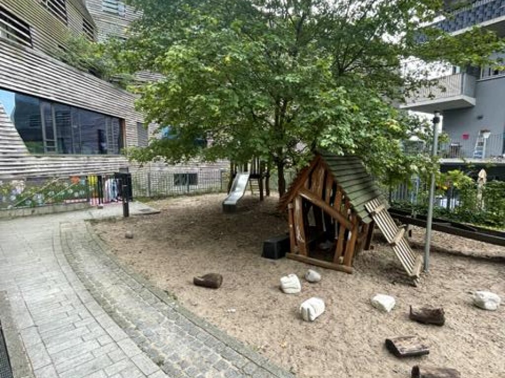 AWO Kita Am Inselpark Außengelände und Spielplatz mit Rutsch und Hütte.