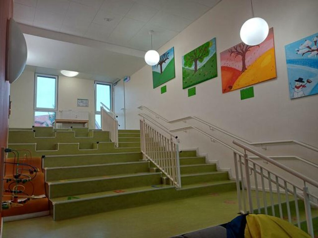 AWO Hamburg Kita Tigerente Treppenbereich mit Sitzmöglichkeiten und Spielelementen an der Wand.