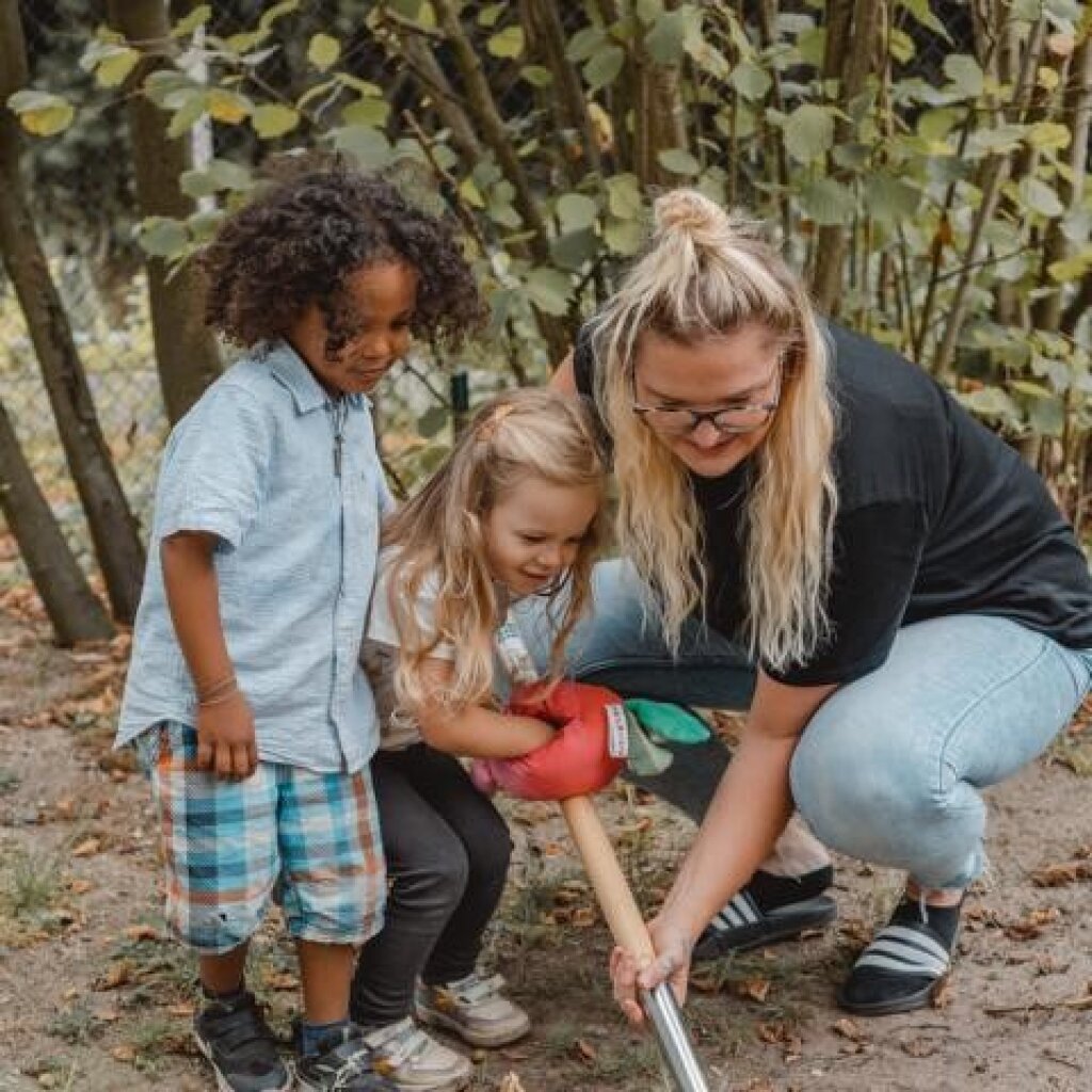 Fachkräfte und Kinder ernten im Garten in der Kita Zauberburg.